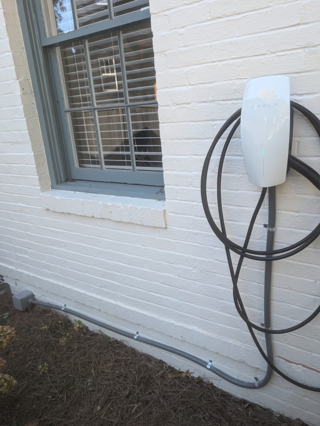 Tesla Wall Connector mounted outdoors with a clean conduit run